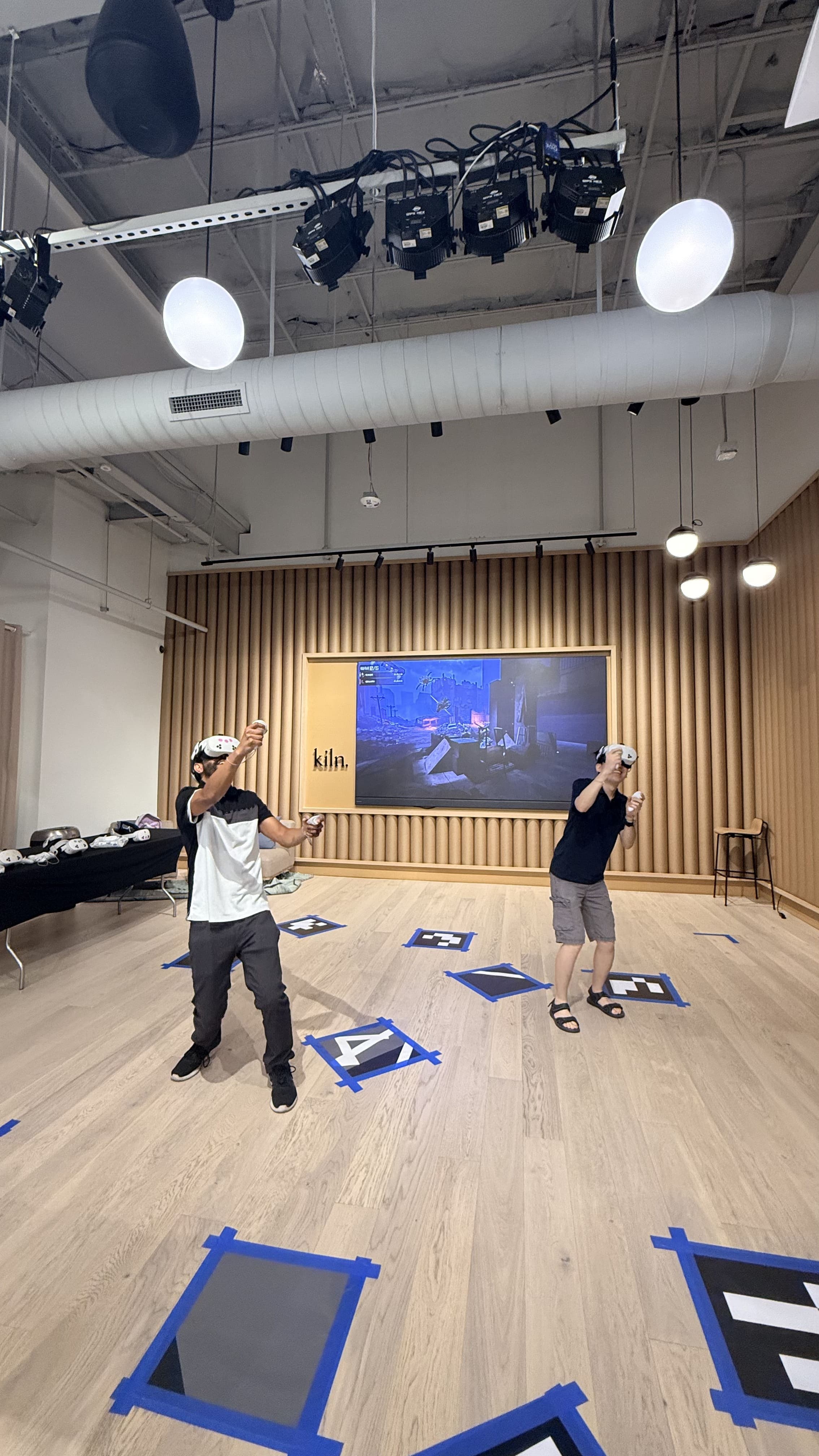 Two players in VR headsets in a mobile VR arena marked out on the floor